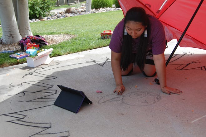 Saundra Hooee gets down on all fours to sketch an outline of her entry in the Chalk Art Festival outside the Farmington Public Library on June 10.
