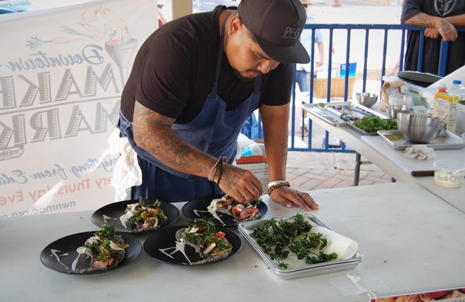 Chef Justin Pioche adds braised kale to the plates he is preparing for judges during the July 15 Northwest New Mexico Local Food Summit cook-off in Orchard Park in downtown Farmington.