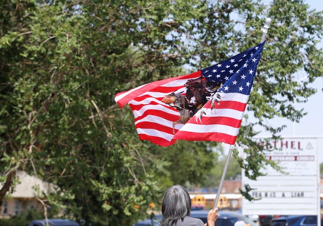 A U.S. flag adorned with a Native American warrior flies on July 19 during the procession to escort family members of U.S. Army veteran Cecelia B. Finona to Shiprock after her remains arrived at Albuquerque earlier in the day.