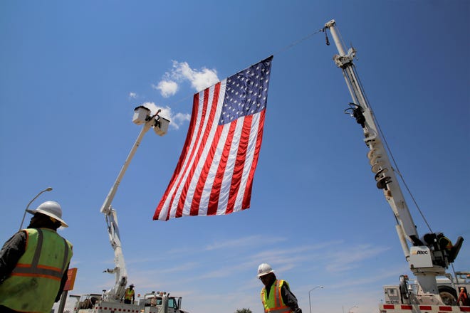 The U.S. flag flies on July 19 over the northbound lane of U.S. Highway 491 in Shiprock. The flag was raised in honor of U.S. Army veteran Cecelia B. Finona as a procession escorts her family to Desert View Funeral Home.