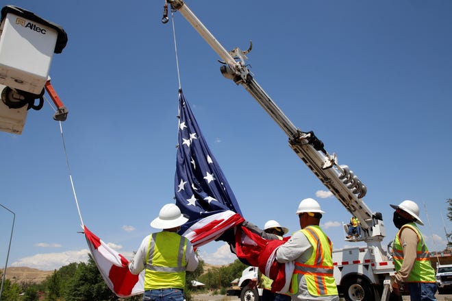 Workers from the Navajo Tribal Utility Authority's Shiprock District raise a U.S. flag on July 19 in honor of the late U.S. Army veteran Cecelia B. Finona over the northbound lane of U.S. Highway 491 in Shiprock.