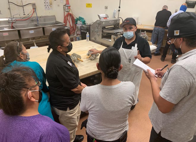 Bakery department employees receive instructions for making doughnuts on July 20 at the new Bashas' Diné Market in Shiprock.