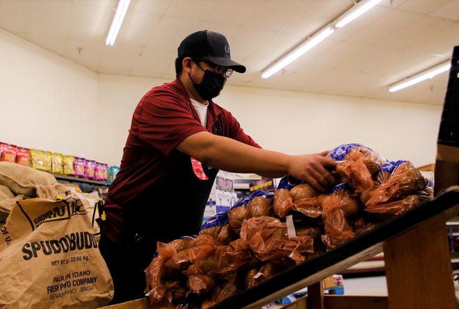 Joseph Begay, produce manager with Bashas' Diné Market's Sanders, Arizona store, helps setup the produce department inside the grocery store chain's new location in Shiprock on July 20.