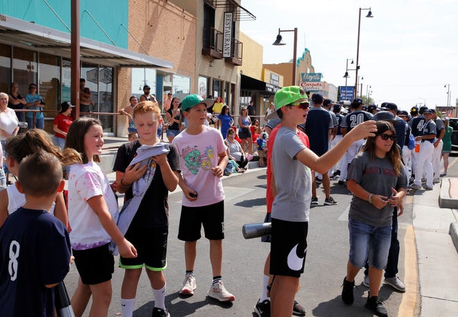 Young spectators wait to receive candy and T-shirts from the D-Bat United team during the 2021 Connie Mack World Series parade on July 22 in downtown Farmington.
