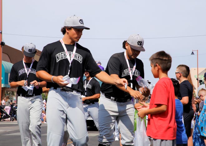 Players from the Colton Nighthawks team hand out jelly bracelets to spectators during the 2021 Connie Mack World Series parade on July 22 in downtown Farmington.