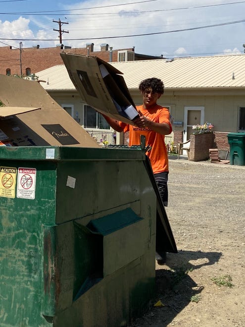 Isaiah Szumlinski of the Aztec Tigers football team hauls away boxes outside an Aztec business during a volunteer clean up effort in downtown Aztec.