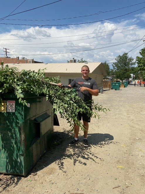 Kayden Lee of the Aztec Tigers football team hauls off some tree trimmings outside a business in downtown Aztec as part of a voluntary clean up effort around the community.
