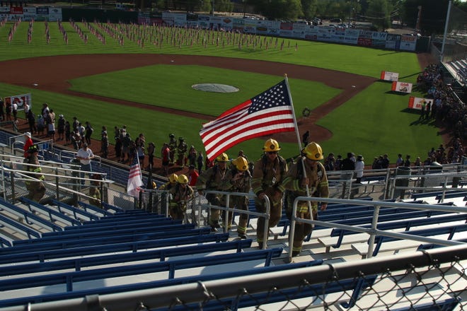 A team of local and area firefighters ascend the bleachers behind home plate at Ricketts Park in honor of the 343 firefighters who lost their lives on Sept. 11, 2001.