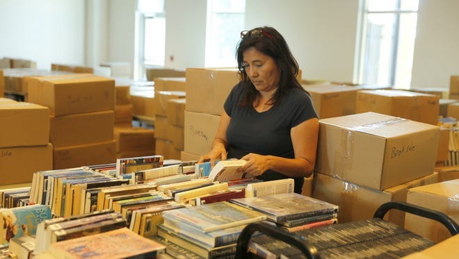 Sharon Blue Eyes of the Farmington Public Library staff sorts books before the annual book sale at the institution in August 2017. The event returns to the library this weekend.