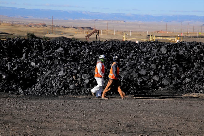 Workers walk in the coal yard at Navajo Mine on Oct. 13. The area is where ticketholders for the Community Heating Resource Program pickup free coal at the mine.