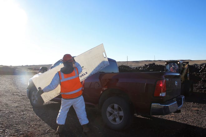 An employee places a board to protect the back window before coal is loaded in the truck bed at Navajo Mine's coal yard on Oct. 13.