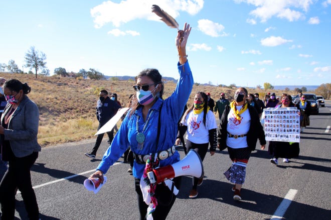 Tisa Bernally holds up a feather while participating in a walk to raise awareness about domestic violence on Oct. 18 in Window Rock, Arizona.