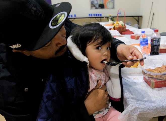 Russell Lewis gives mashed potatoes to his daughter, Enuriya Lewis, 1, at the Salvation Army's annual Thanksgiving luncheon on Nov. 25 at Sycamore Park Community Center in Farmington.