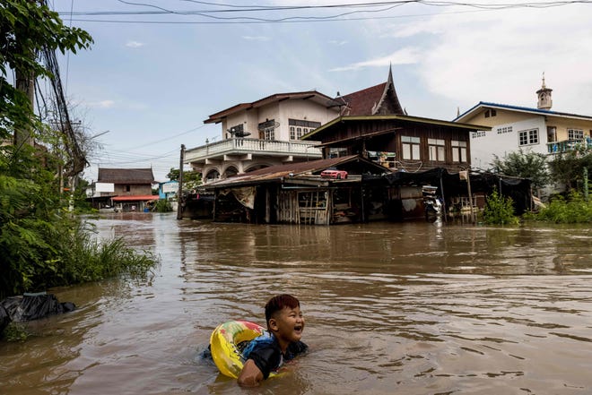 In this file photograph taken on Oct. 4, 2021, a child wears a float as he swims in floodwaters of a neighborhood in Ayutthaya, Thailand, after tropical storm Dianmu caused flooding in 31 provinces across the country.