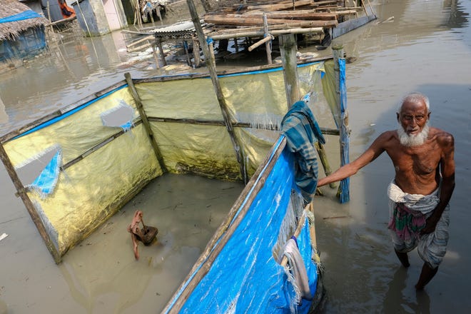 An elderly man stands by a tube well buried in water during high tide in Pratap Nagar, in Shyamnagar region of Satkhira district, Bangladesh on Oct. 5, 2021. A United Nations Intergovernmental Panel on Climate Change report released on Monday, Feb. 28, 2022, says a staggering 143 million people will be uprooted over the next 30 years by rising seas, searing temperatures and other climate calamities.