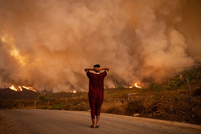 In this file photograph taken on Aug. 15, 2021, a bystander looks at wildfires tearing through a forest in the region of Chefchaouen in northern Morocco.