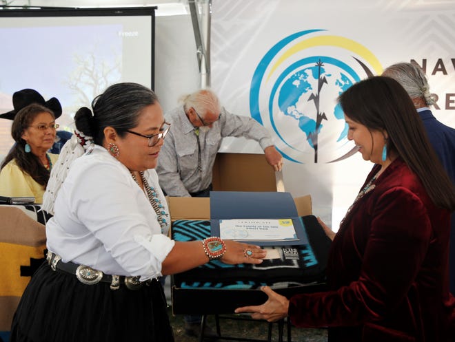 At left, Shawna Becenti, the head of school at Navajo Preparatory School, presents a 30th anniversary commemorative blanket to April Hale, former board of trustees member and daughter of former tribal President Albert Hale, on May 12 in Farmington.