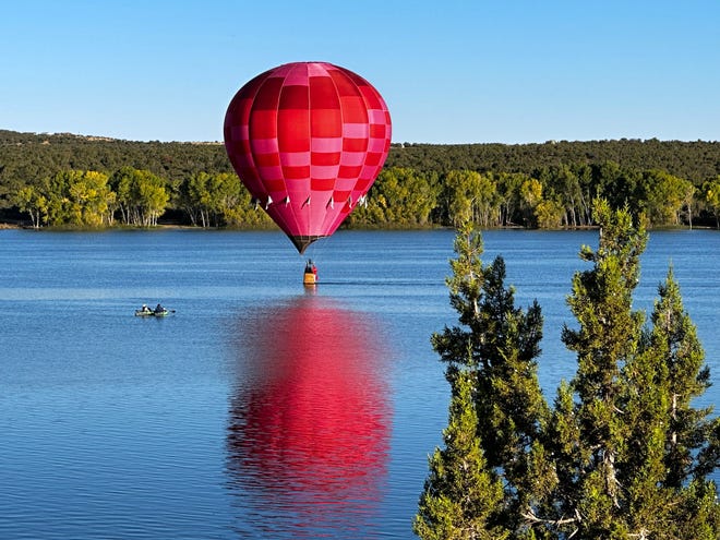 Kayakers watch as this colorful balloon takes a long skim across part of Lake Farmignton before taking to the air Sept. 24 during the Four Corners Balloon Rally.