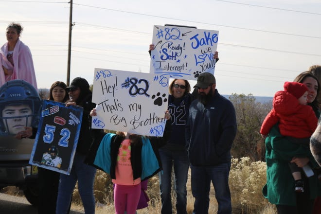 Family members of Piedra Vista High School football team player Jacob Schreuder line the road leaving the high school on Friday, Nov. 18, 2022 as they leave for a long road trip to Roswell and a Class 5A semifinal game on Saturday at the Wool Bowl against the Coyotes.